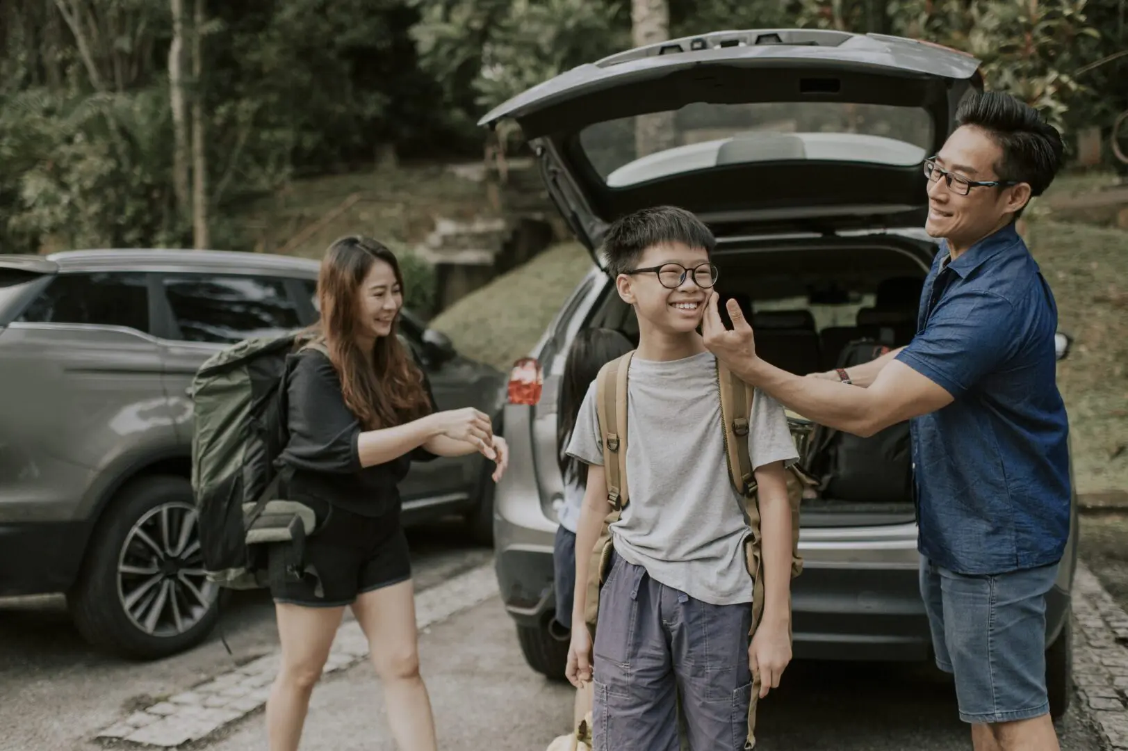 an asian chinese father getting ready for hiking packing from his car boot with his family